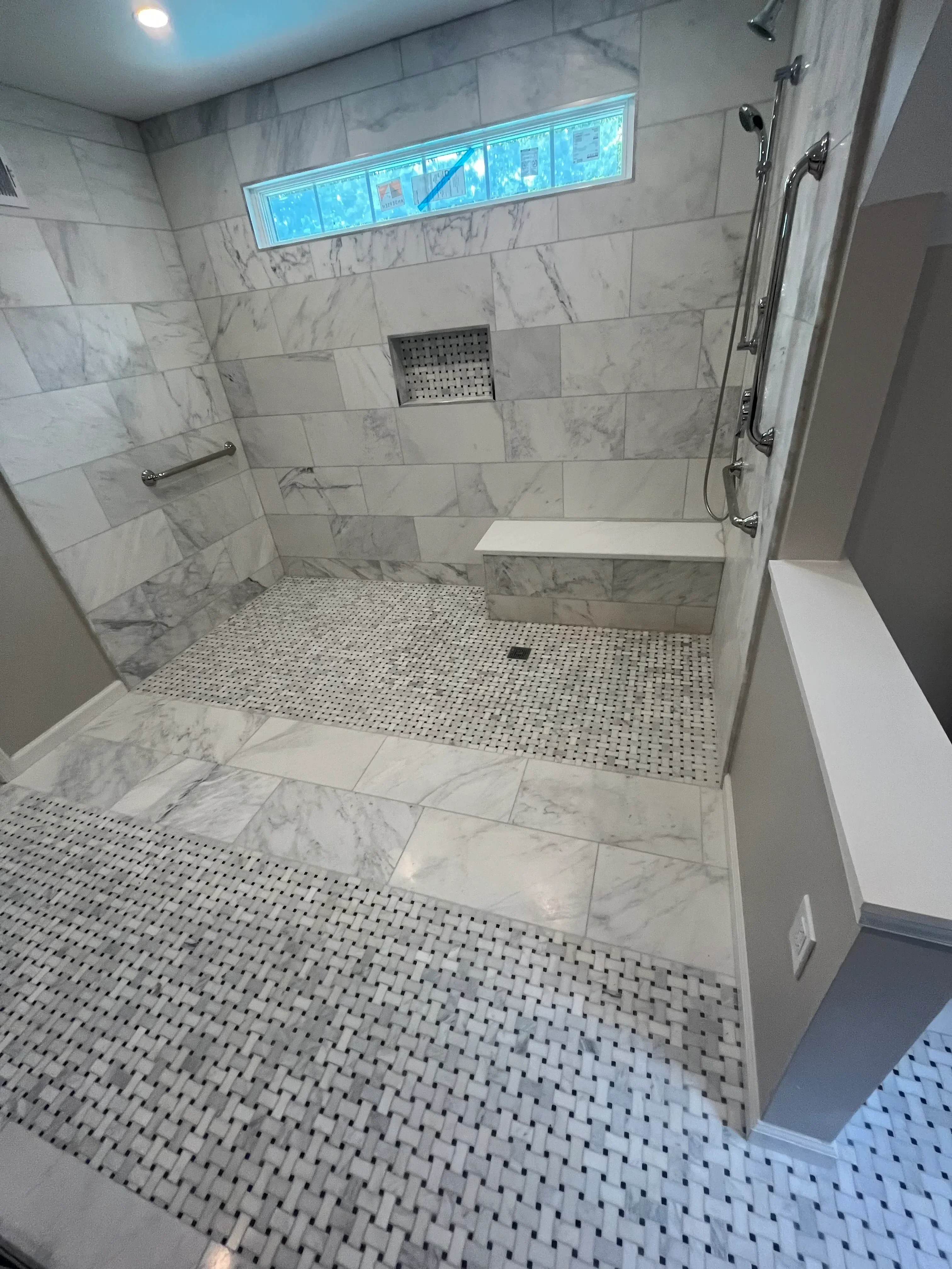 Marble tile shower with mosaic penny tile accent wall and frameless glass enclosure