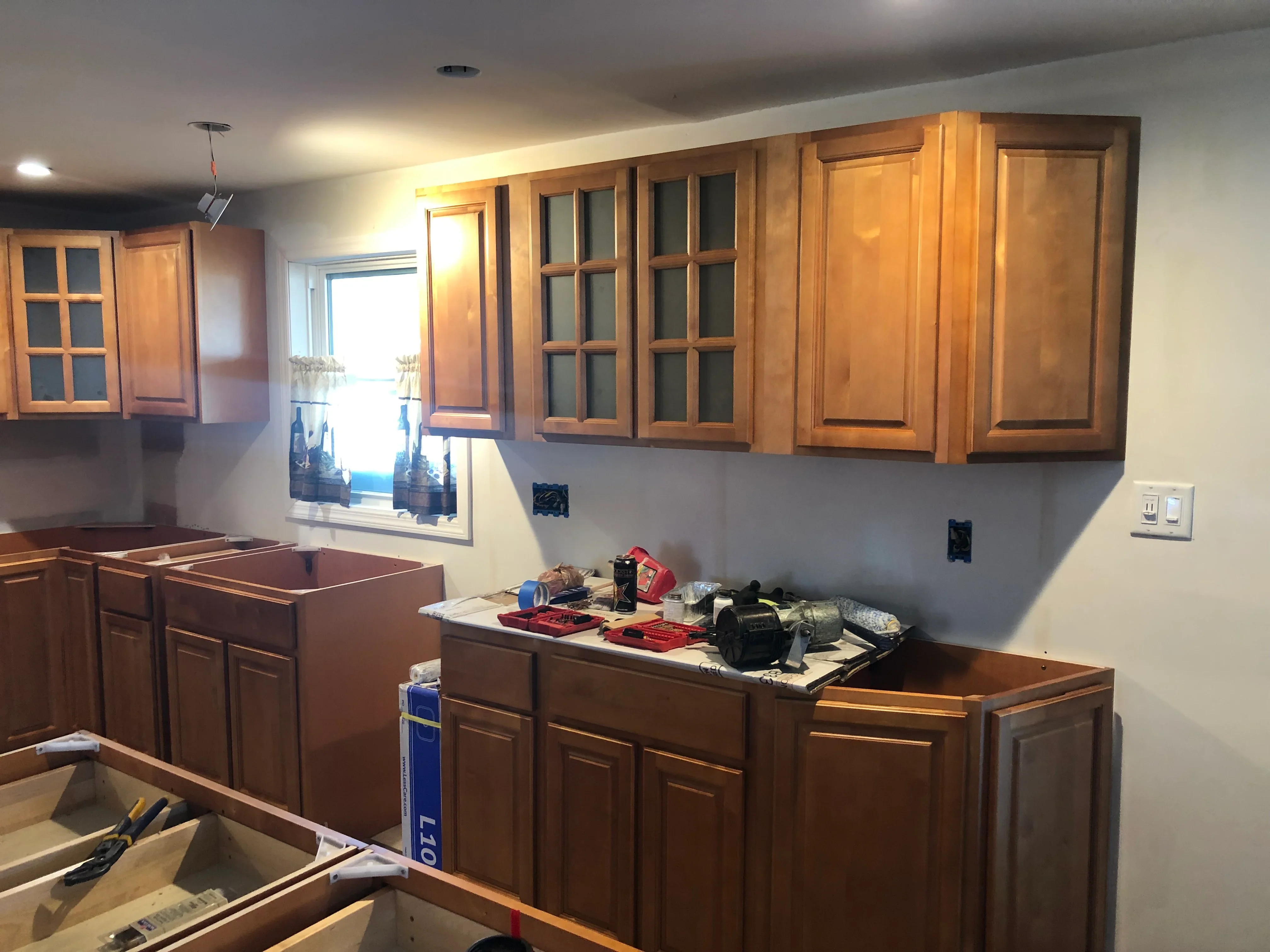 Cherry wood kitchen cabinets with glass-front uppers and raised panel lowers, recessed lighting, and new electrical outlets