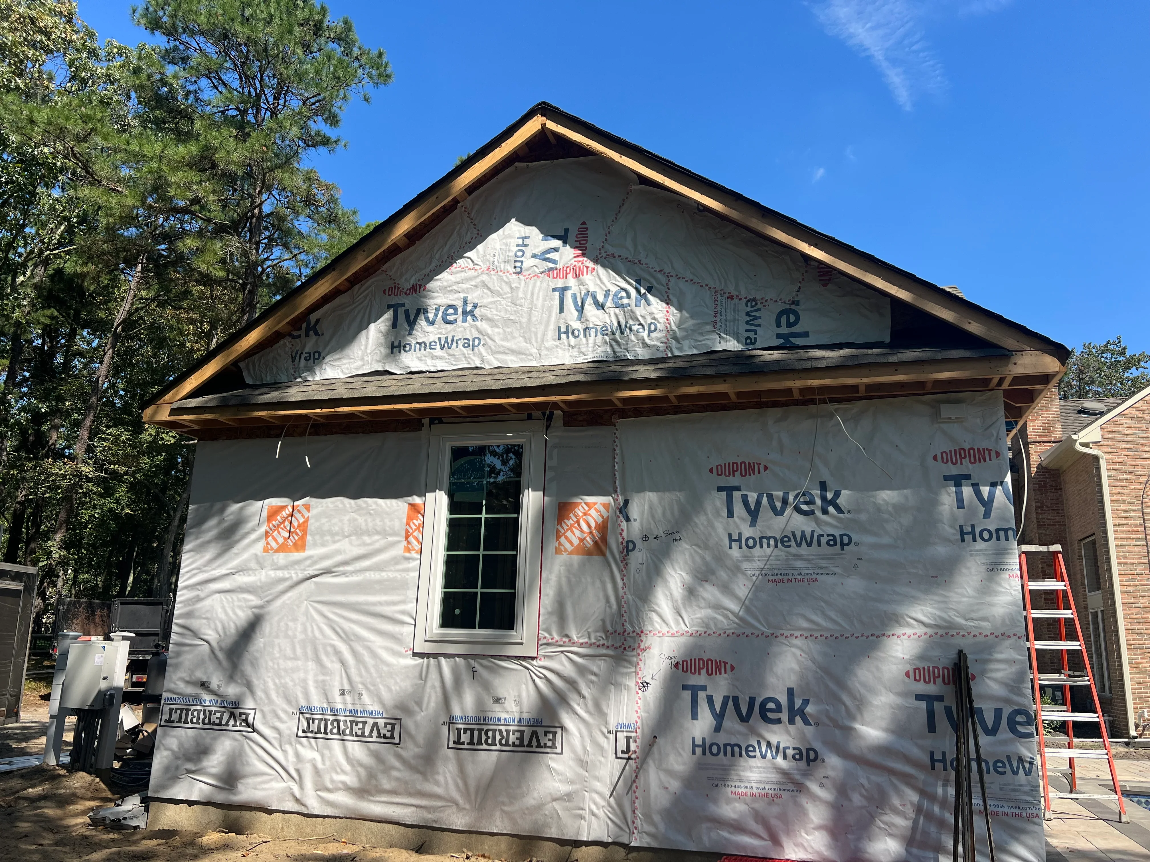 Brick home wrapped in white Tyvek HomeWrap with sealed seams and protective covering during construction