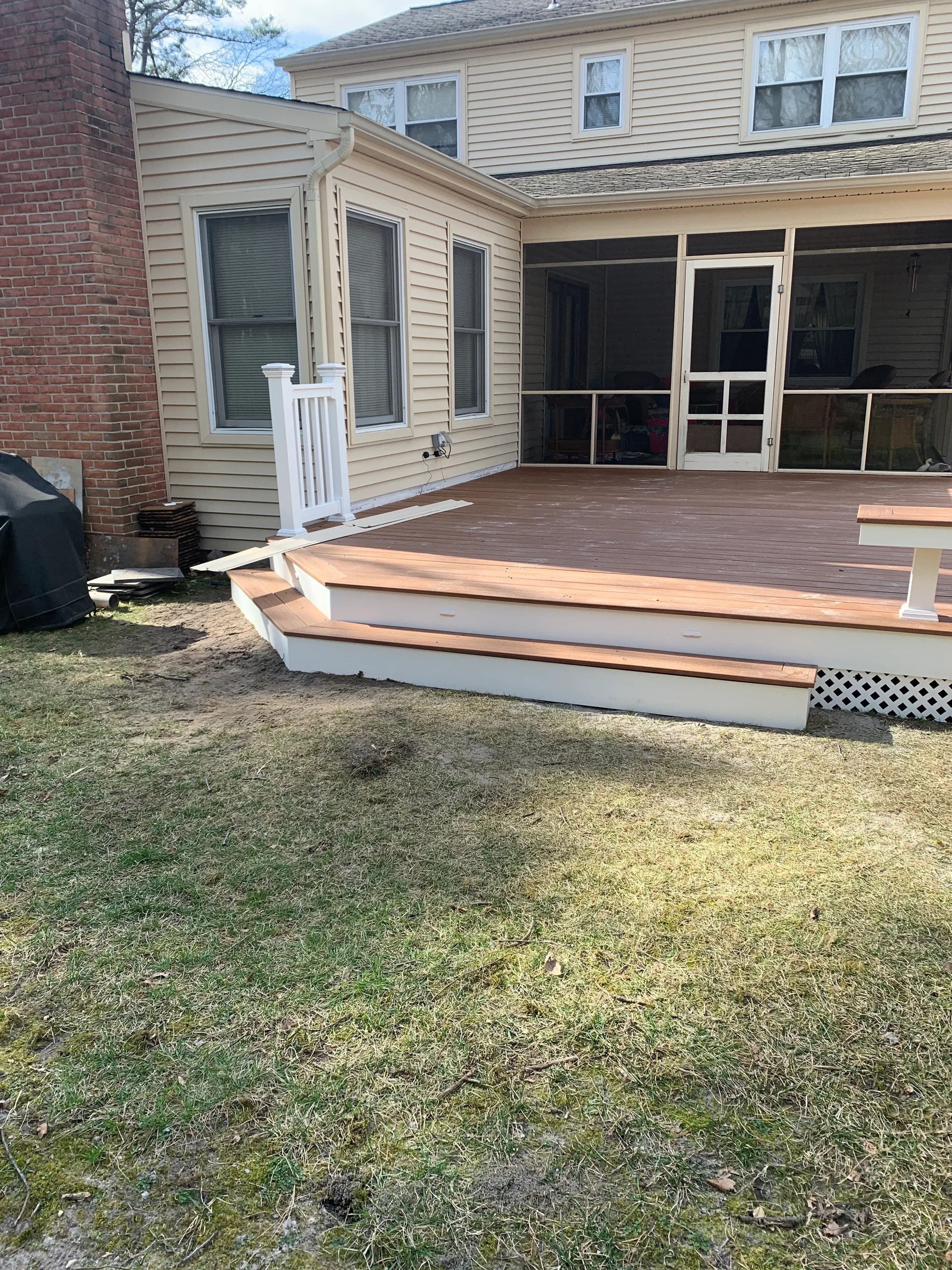Tan corrugated metal siding with vinyl windows and brick foundation on residential home