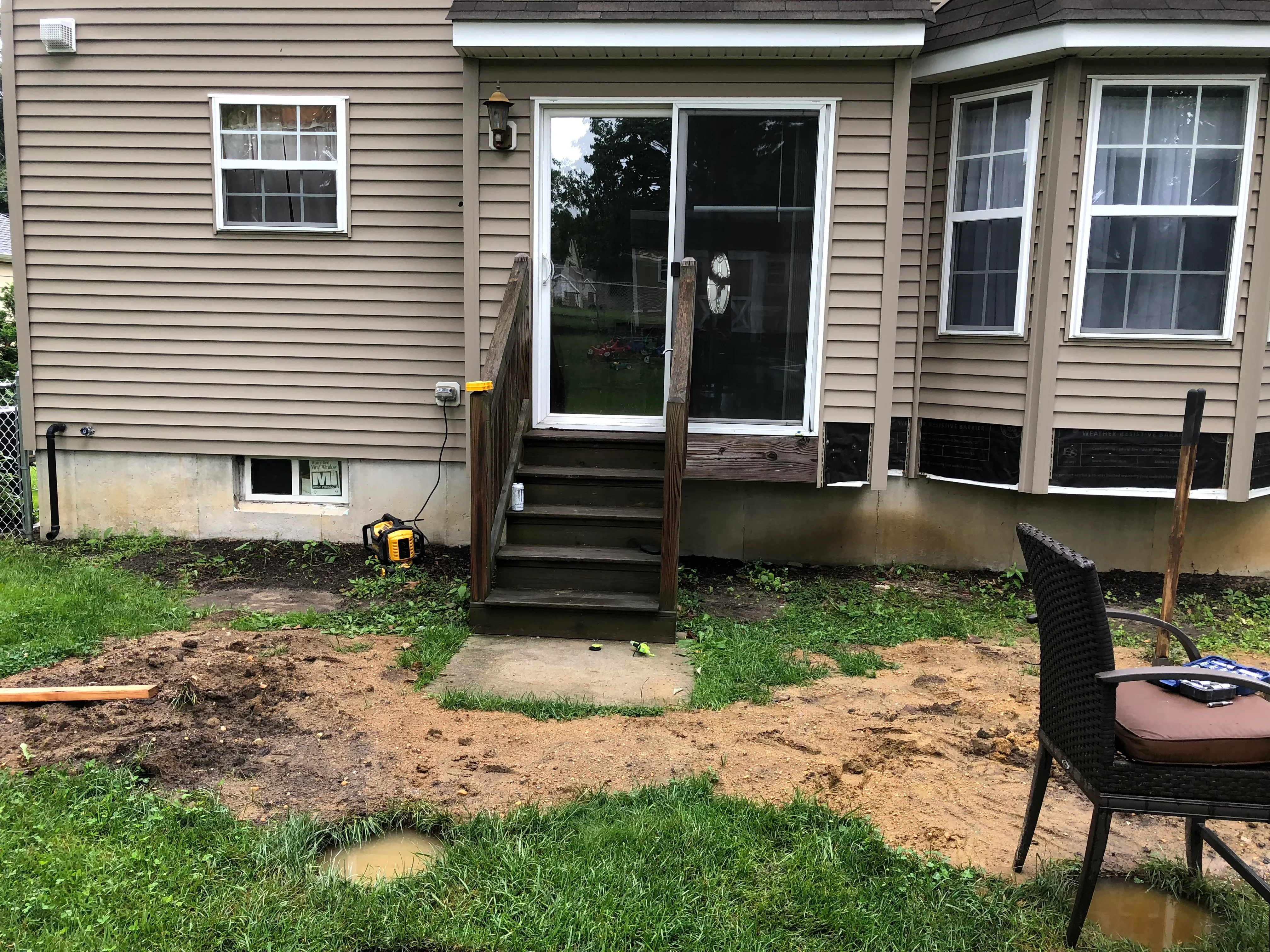 Foundation excavation and grading work with exposed soil and drainage preparation