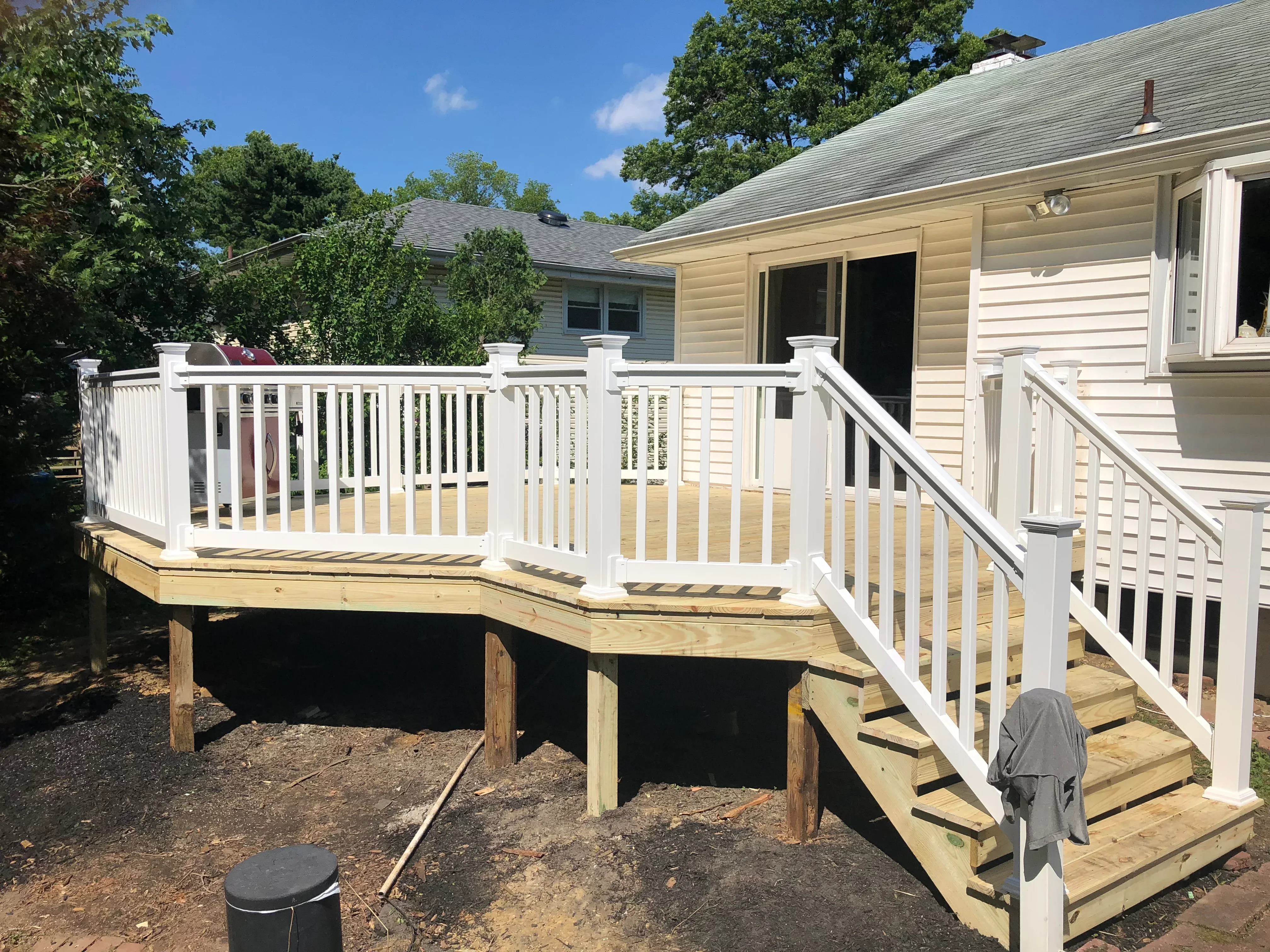 Elevated wooden deck with white vinyl railings and stairs attached to residential home