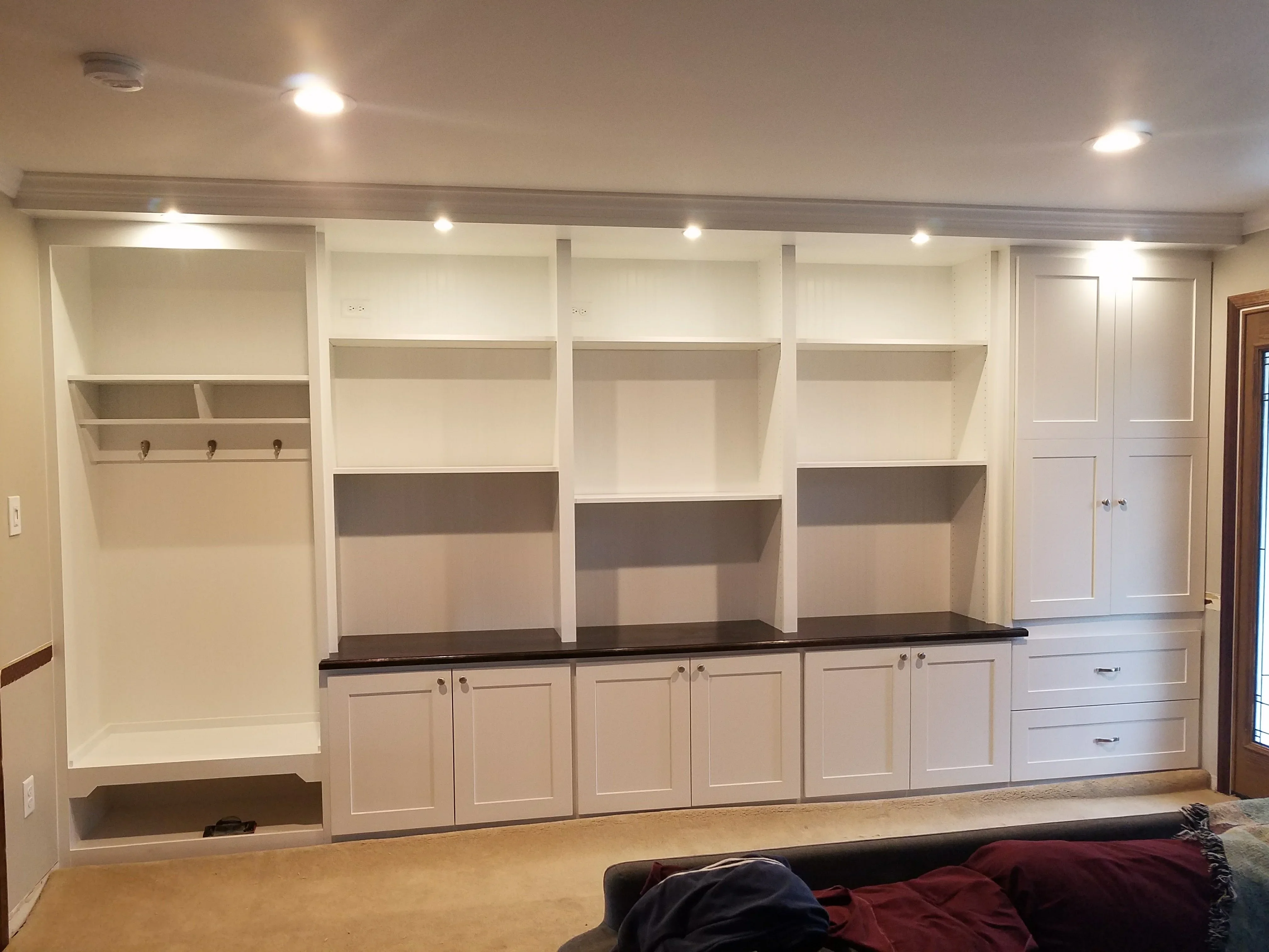 White built-in cabinetry with dark countertop, open shelving, and recessed lighting in finished basement