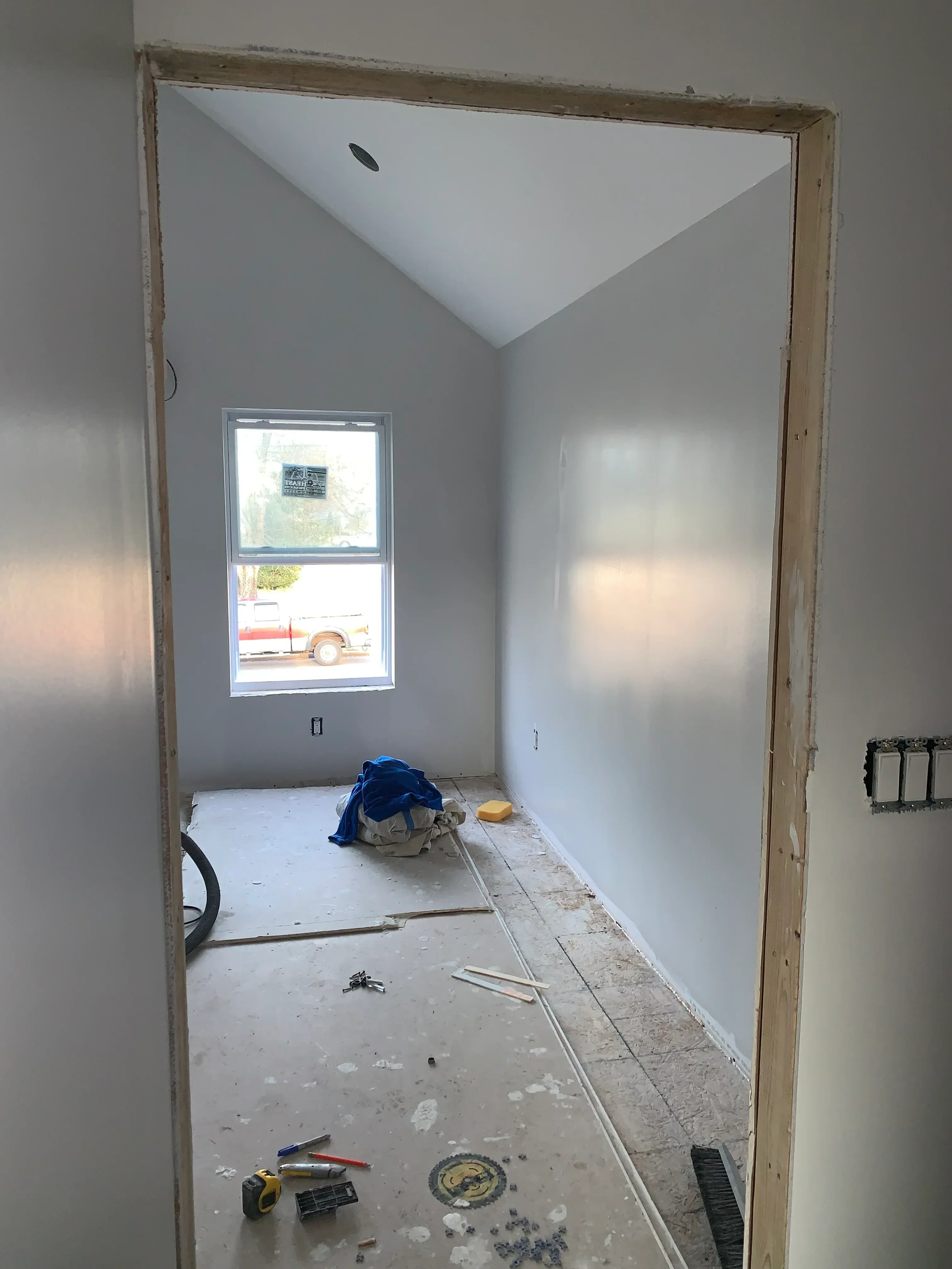 Drywall ceiling and wall installation with taped joints, primer, and casement window opening