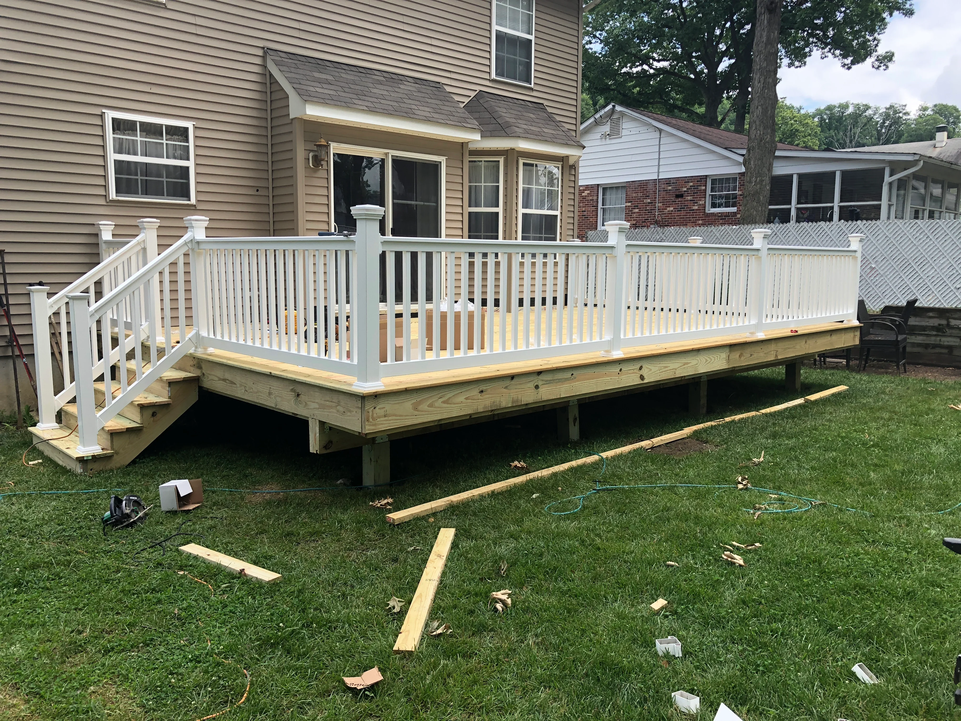 Elevated composite deck with white vinyl railing and stairs during construction