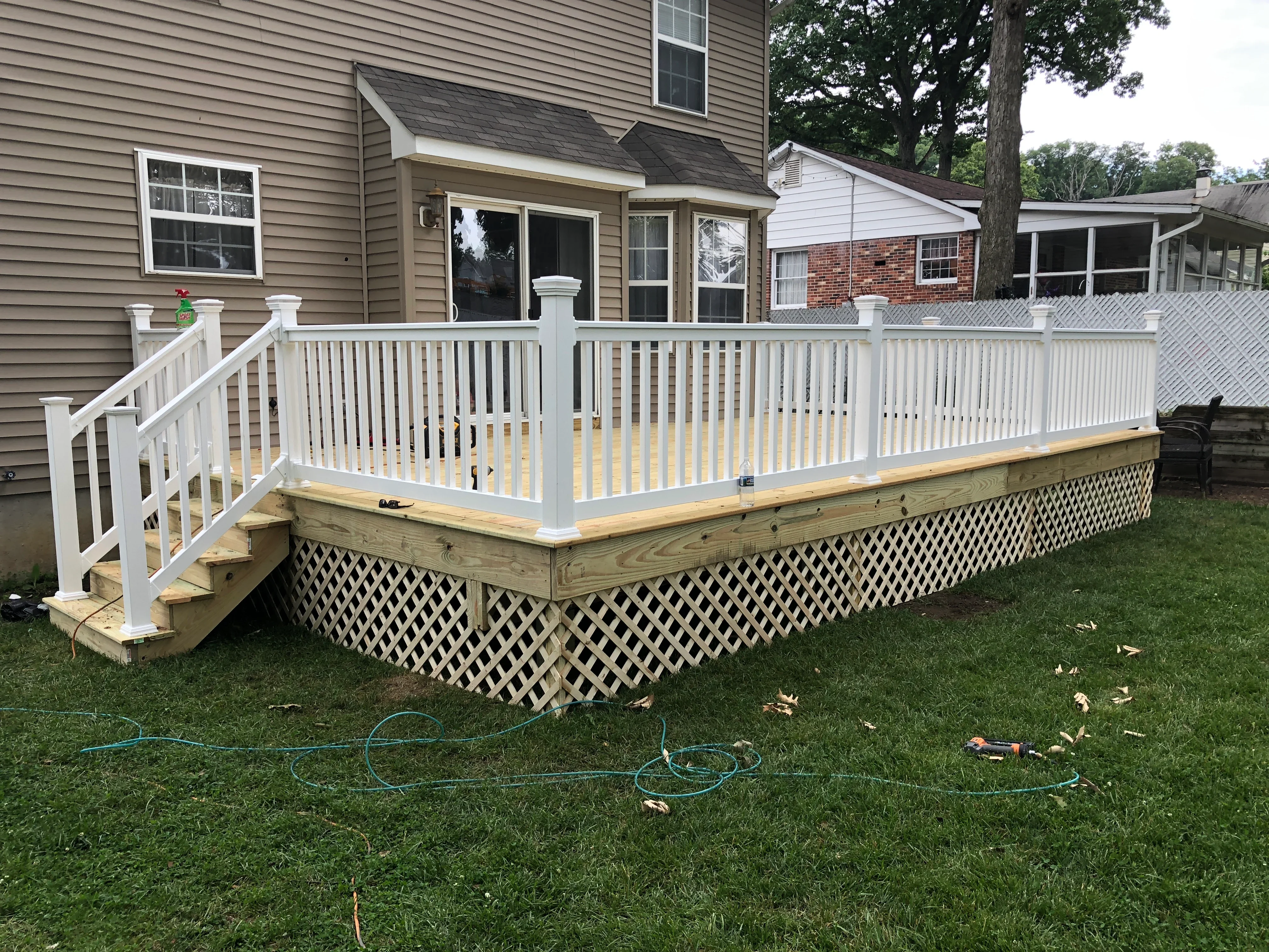 Elevated deck with white vinyl railings, pressure-treated frame, and lattice skirting